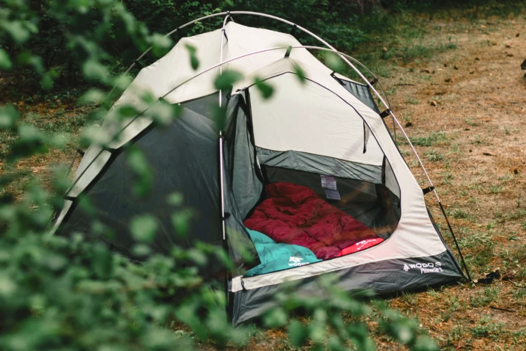 a tent at a camping spot zipped open to reveal sleeping bags.