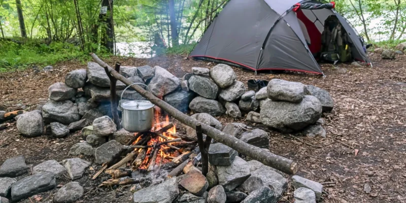 a photo of a tent next to a fire pit following the theme of 10 camping hacks