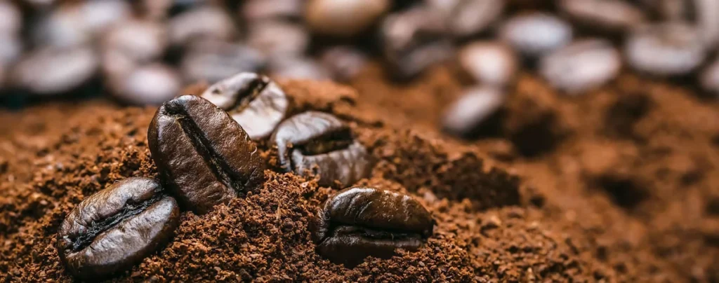 a photo of some whole bean coffee sitting on top of some ground coffee. Used as accent image for this article on camp coffee